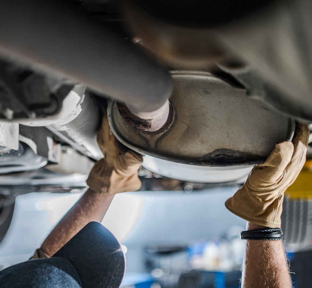 A man inspects the engine of a car, focused on repairs while working under the hood in a well-lit garage.