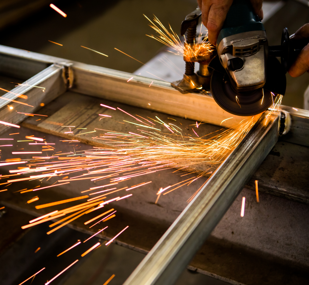 A person using a grinder to grind metal, sparks flying as they work diligently in a workshop setting.